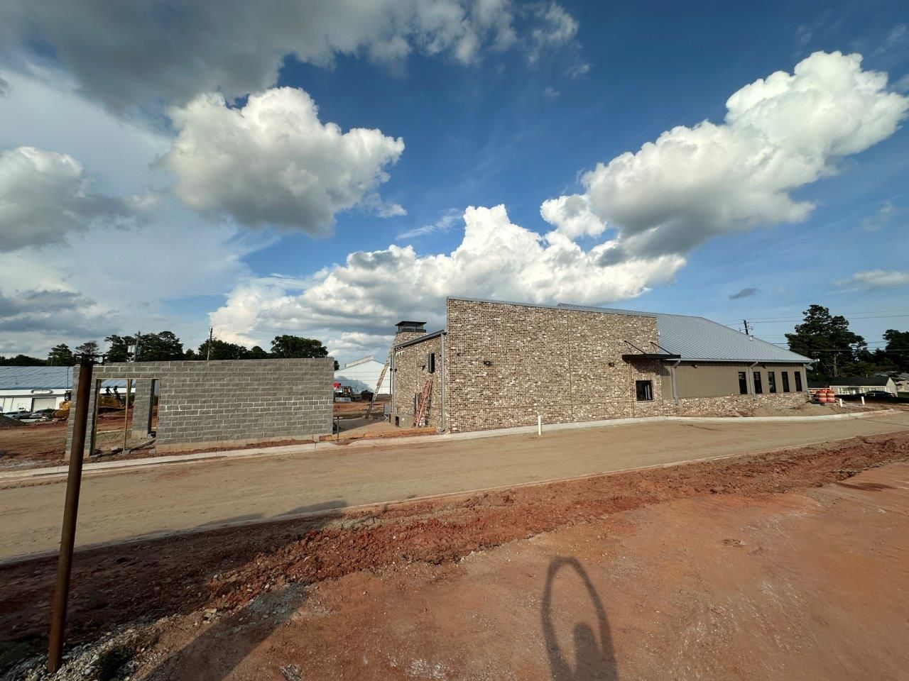 A shadow of a person is cast on the ground in front of a building under construction