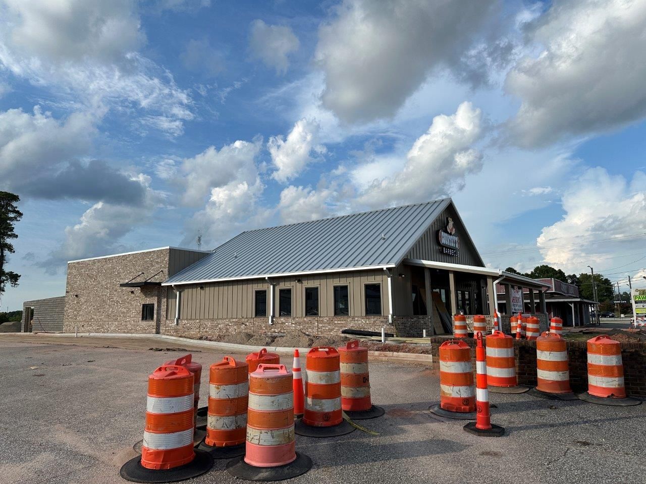 A building under construction with orange and white cones in front of it.
