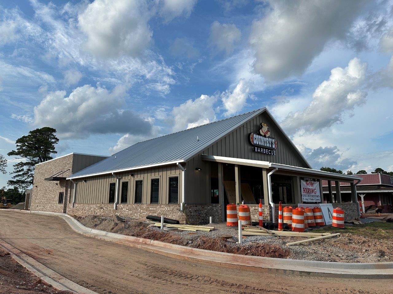 A large building under construction with a metal roof and a porch.