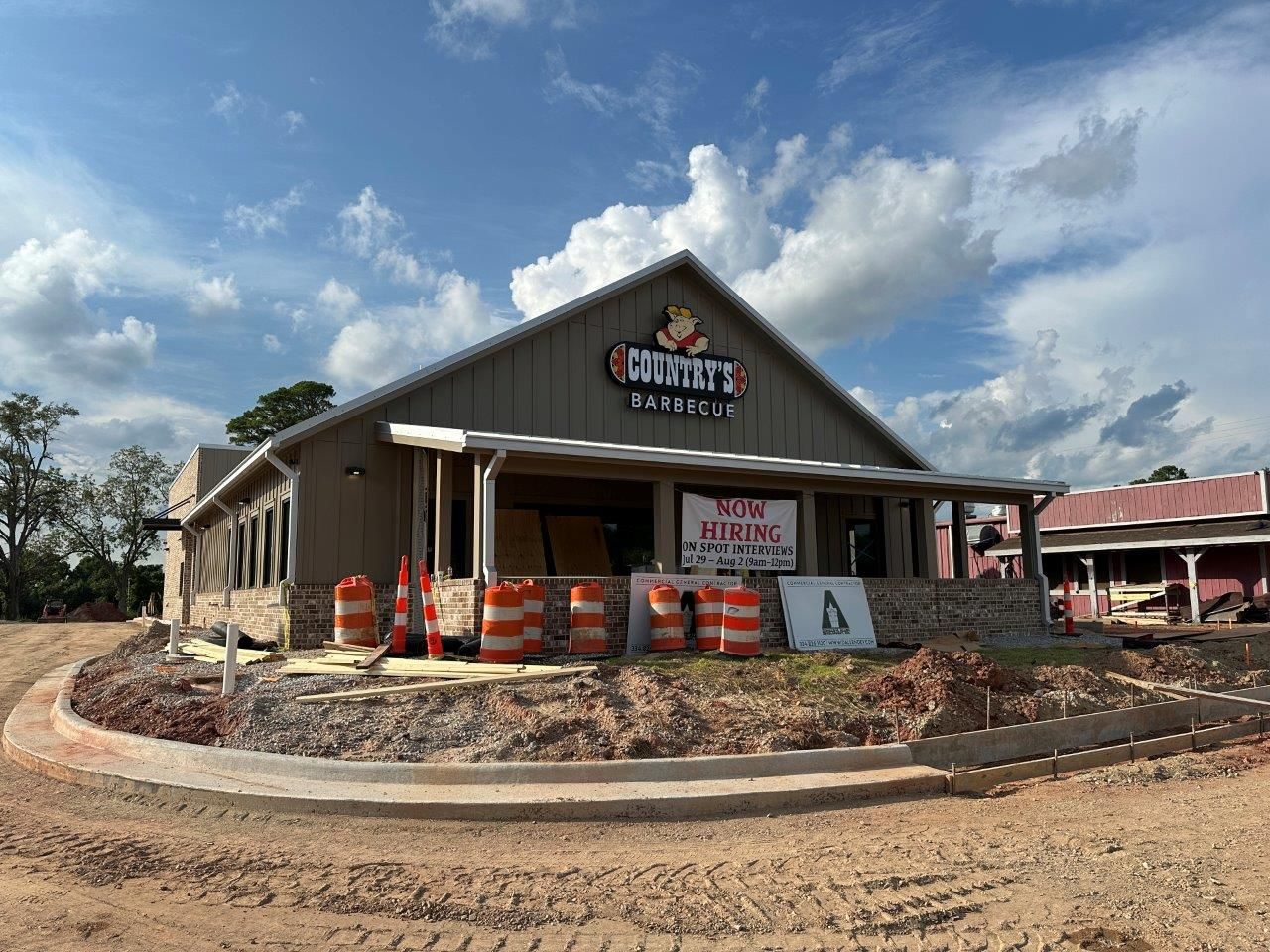 A large building is being built in the middle of a dirt field.