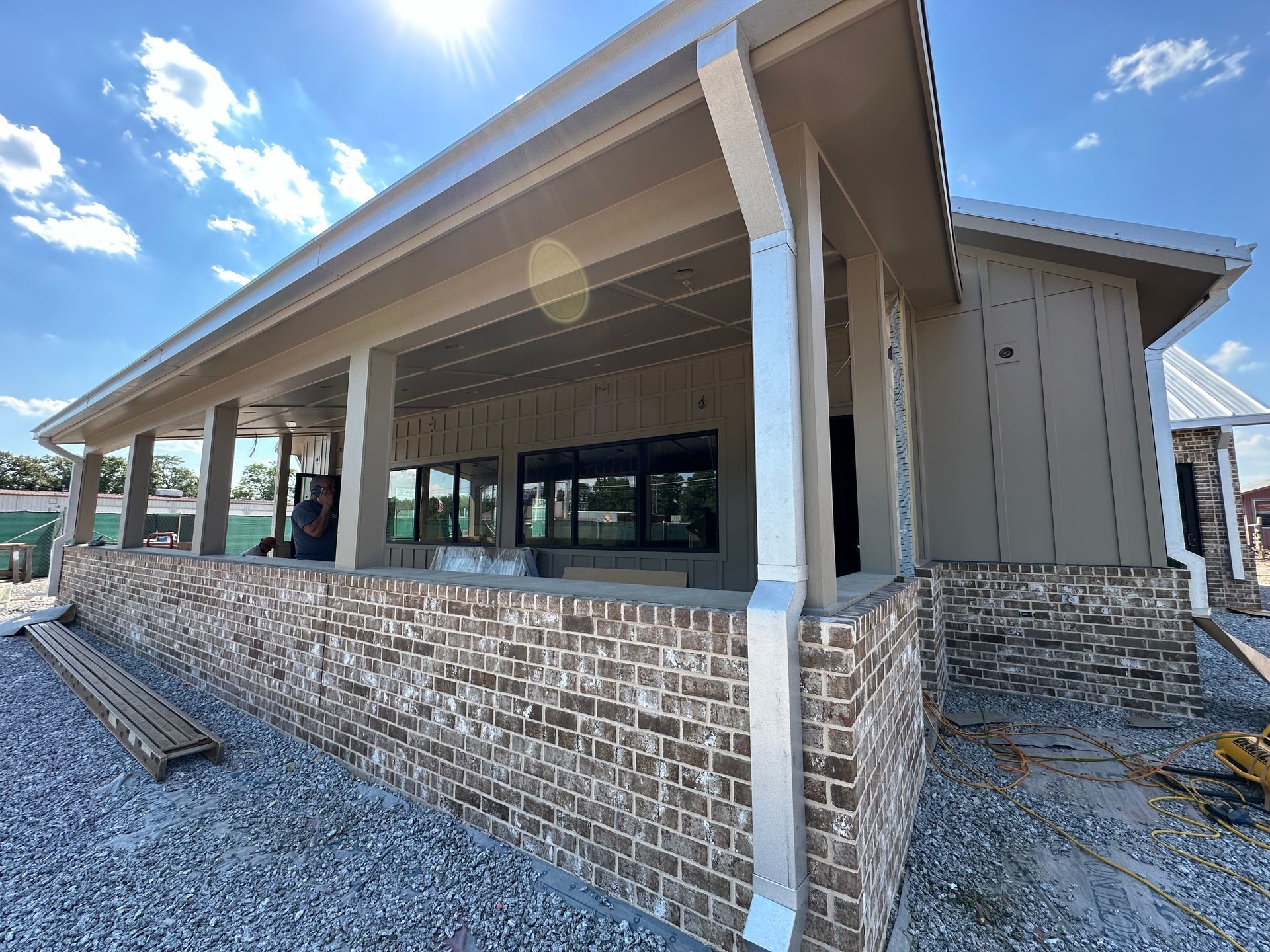 A man is standing on a porch of a house under construction.