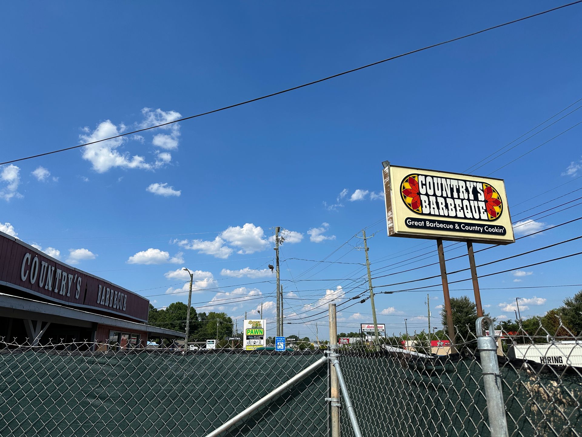 A chain link fence surrounds a building with a sign in front of it.
