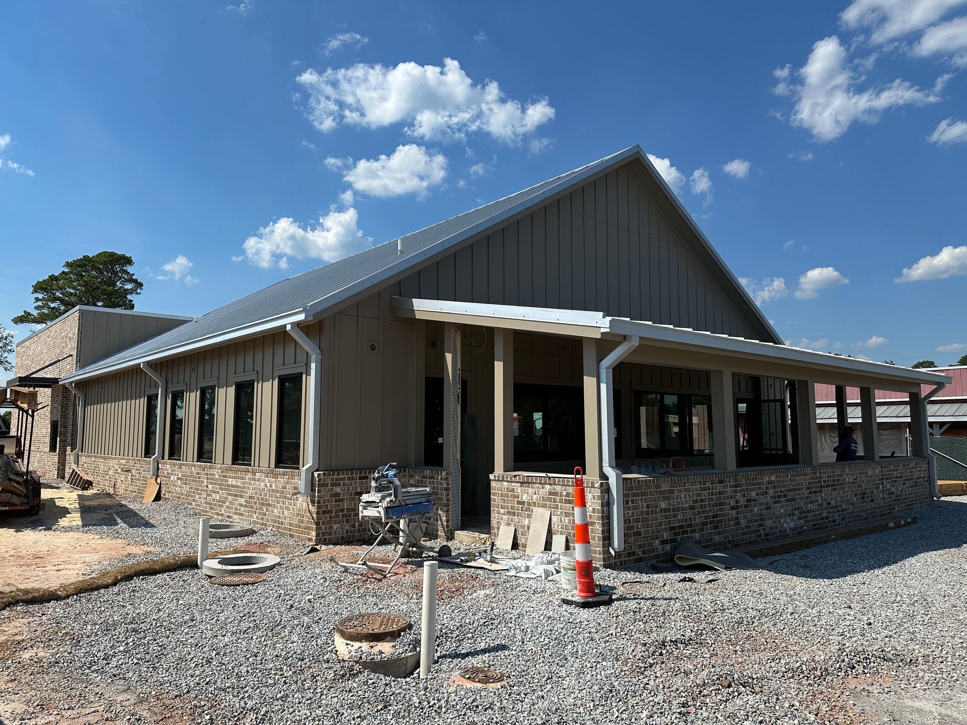 A large building under construction with a metal roof and a porch.