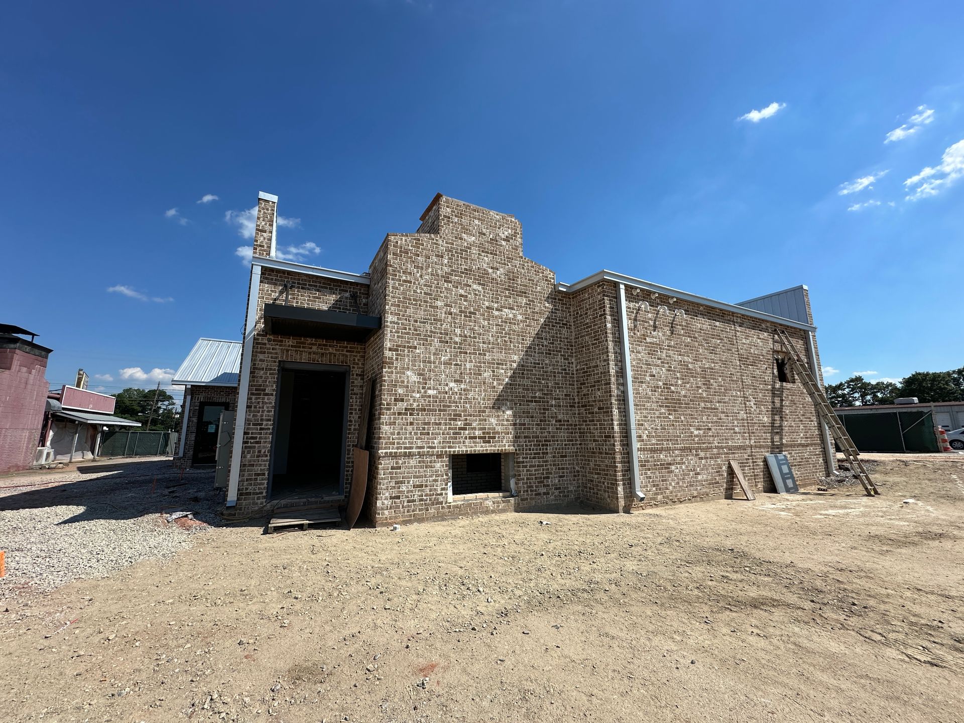 A large brick building is sitting in the middle of a dirt field.