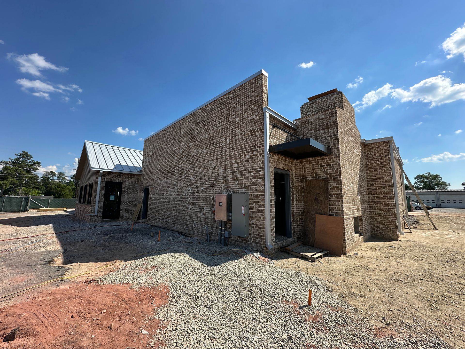 A brick building is being built in a dirt field.