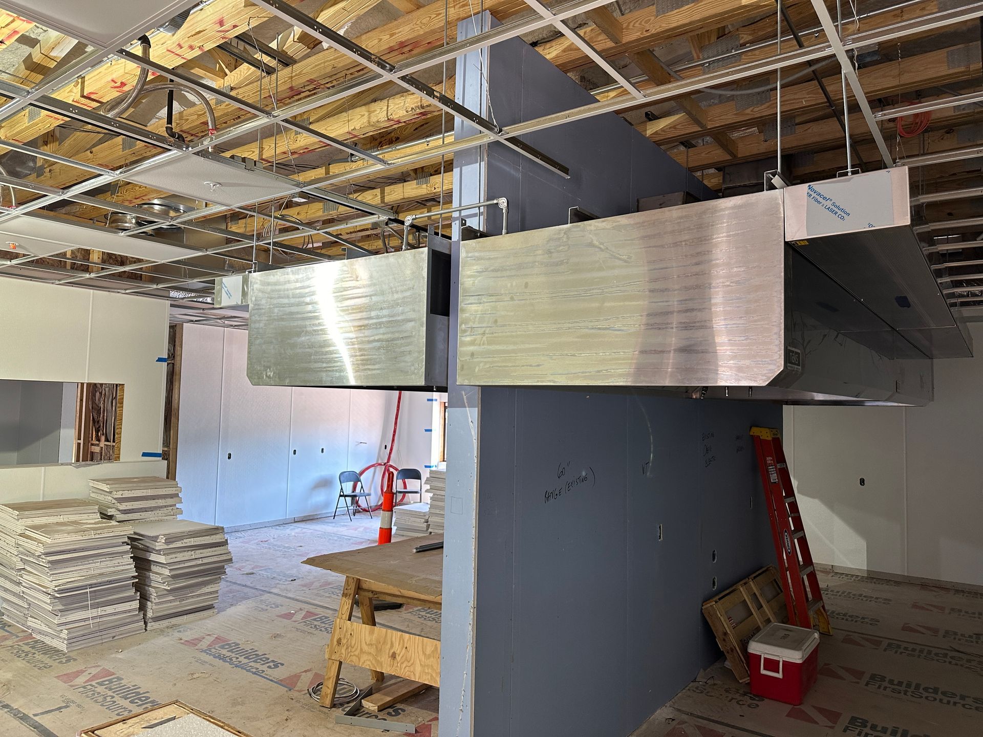 A room under construction with a ladder and a red cooler.