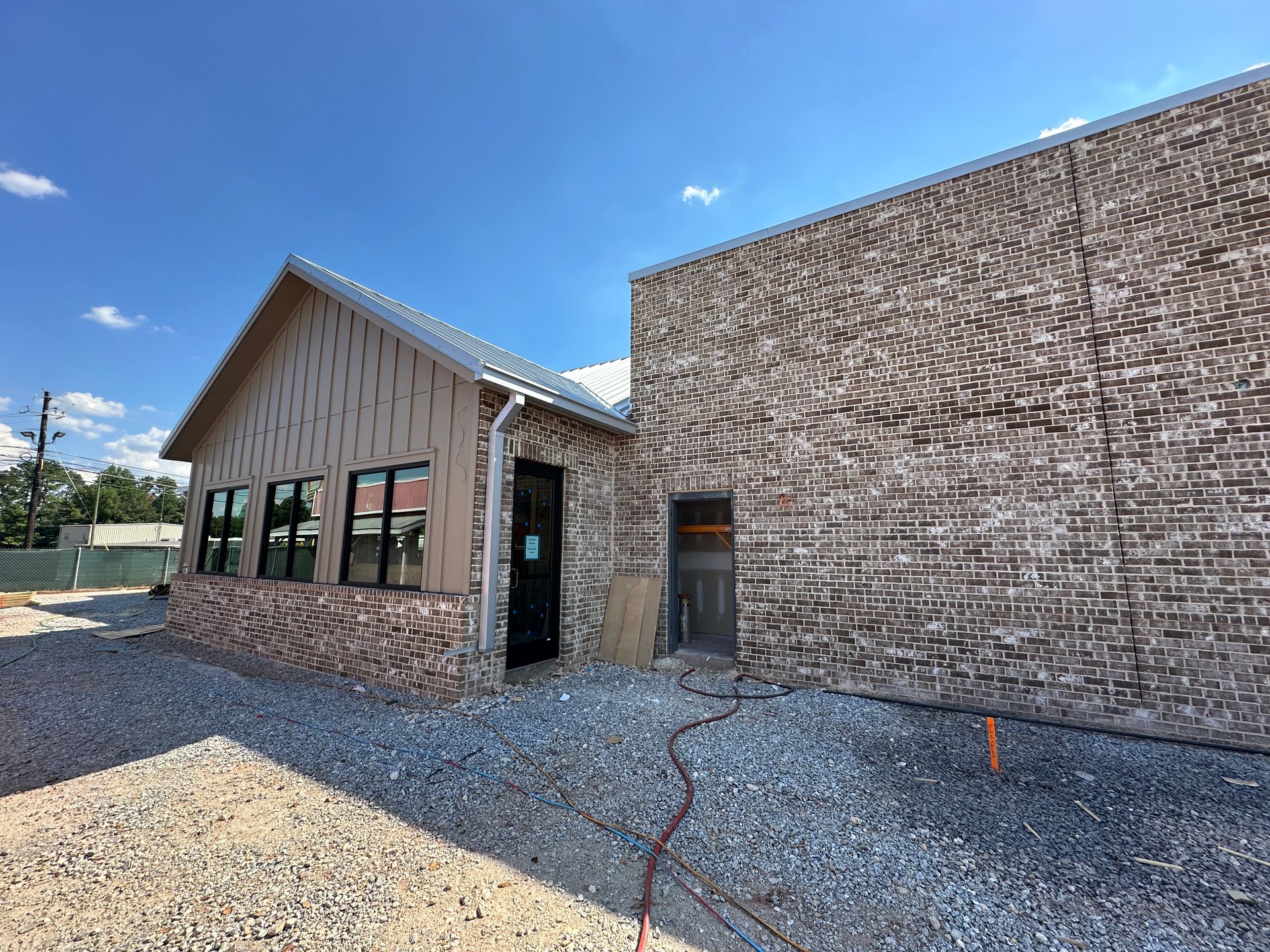 A brick building with a roof and a lot of windows is being built.