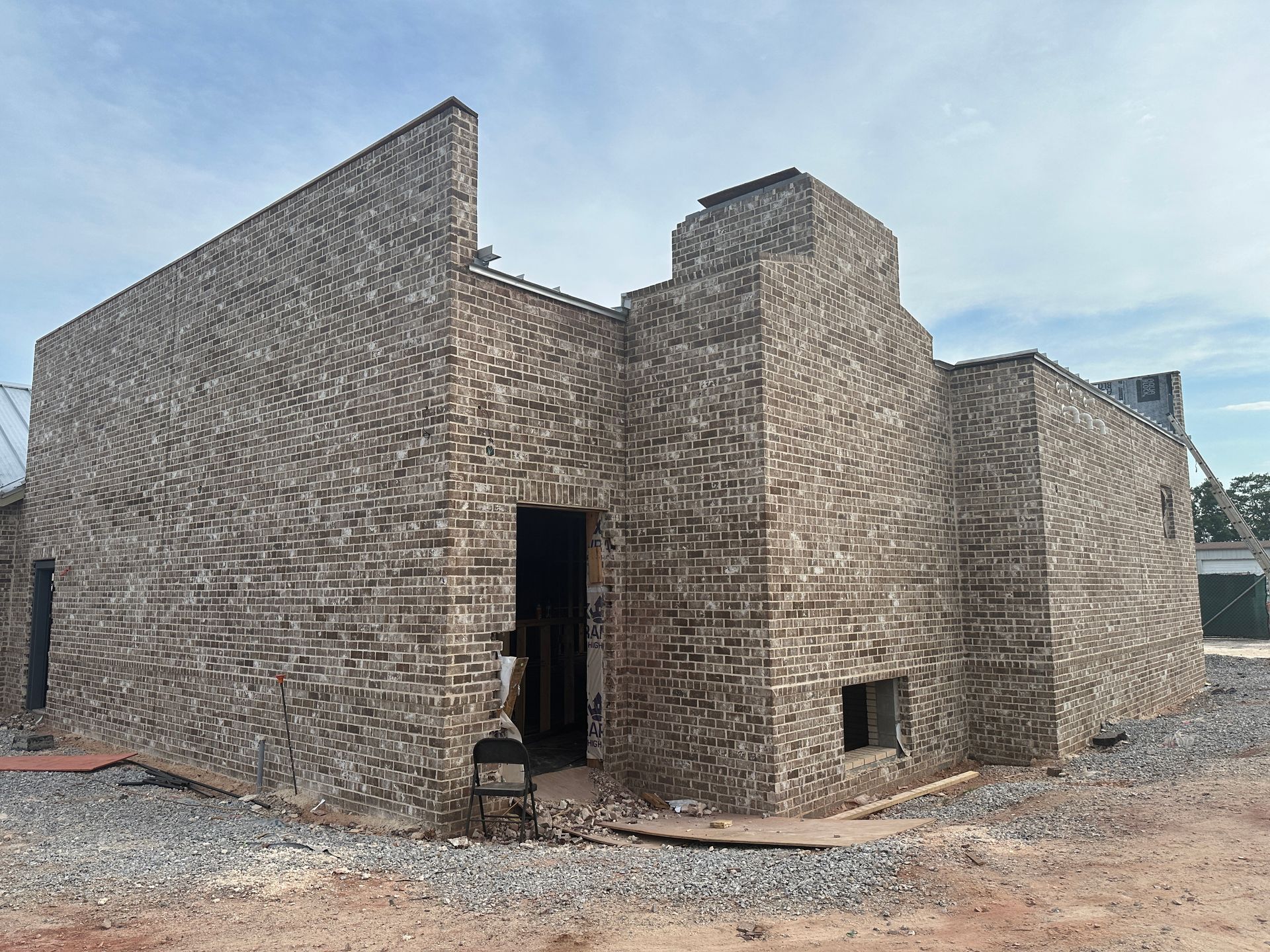 A large brick building is being built in a dirt field.