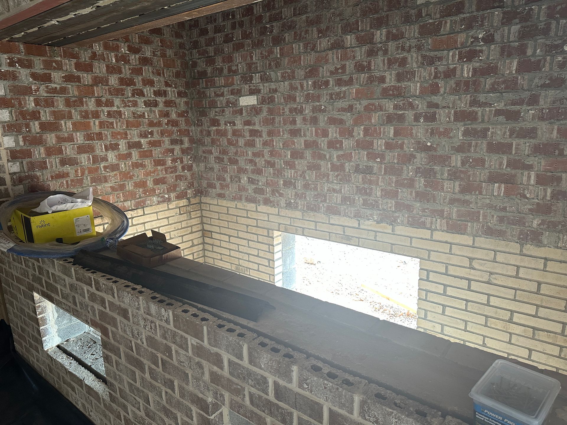 A room with a brick wall and two windows.