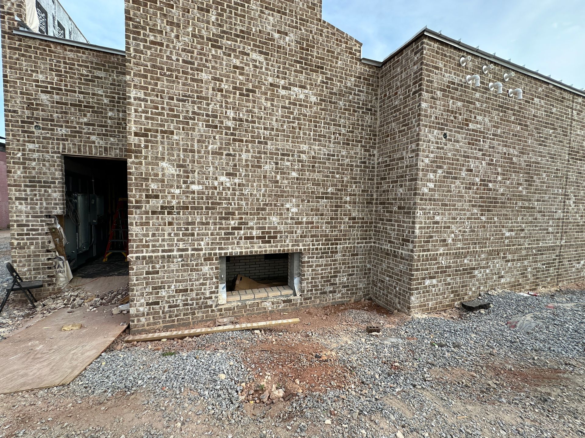 A large brick building with a small window in the middle of it is being built.