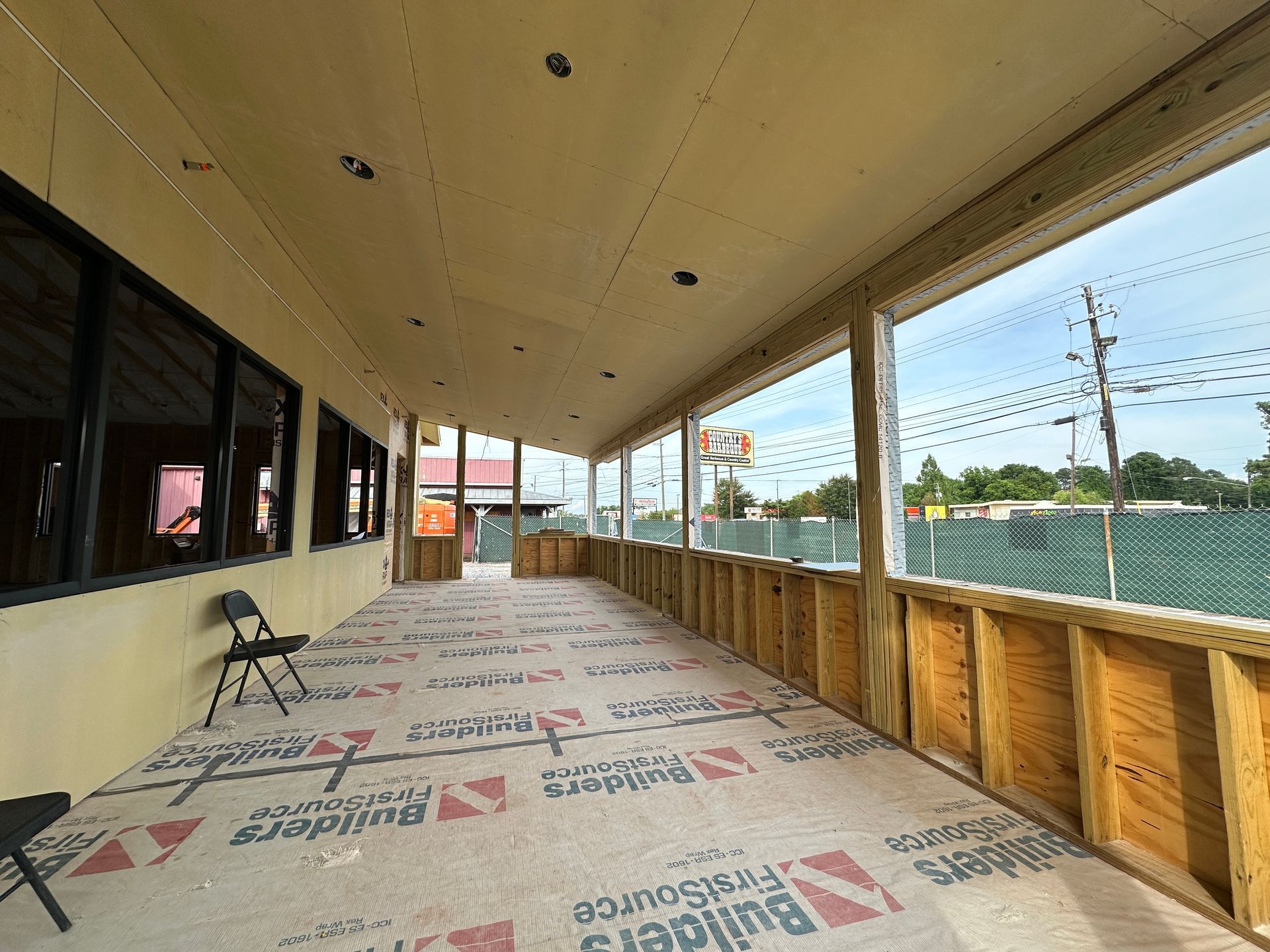 A long hallway with a lot of windows and a chair.