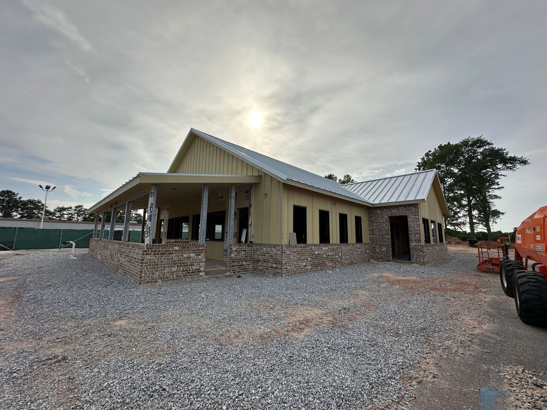 A large building is being built on a gravel lot.