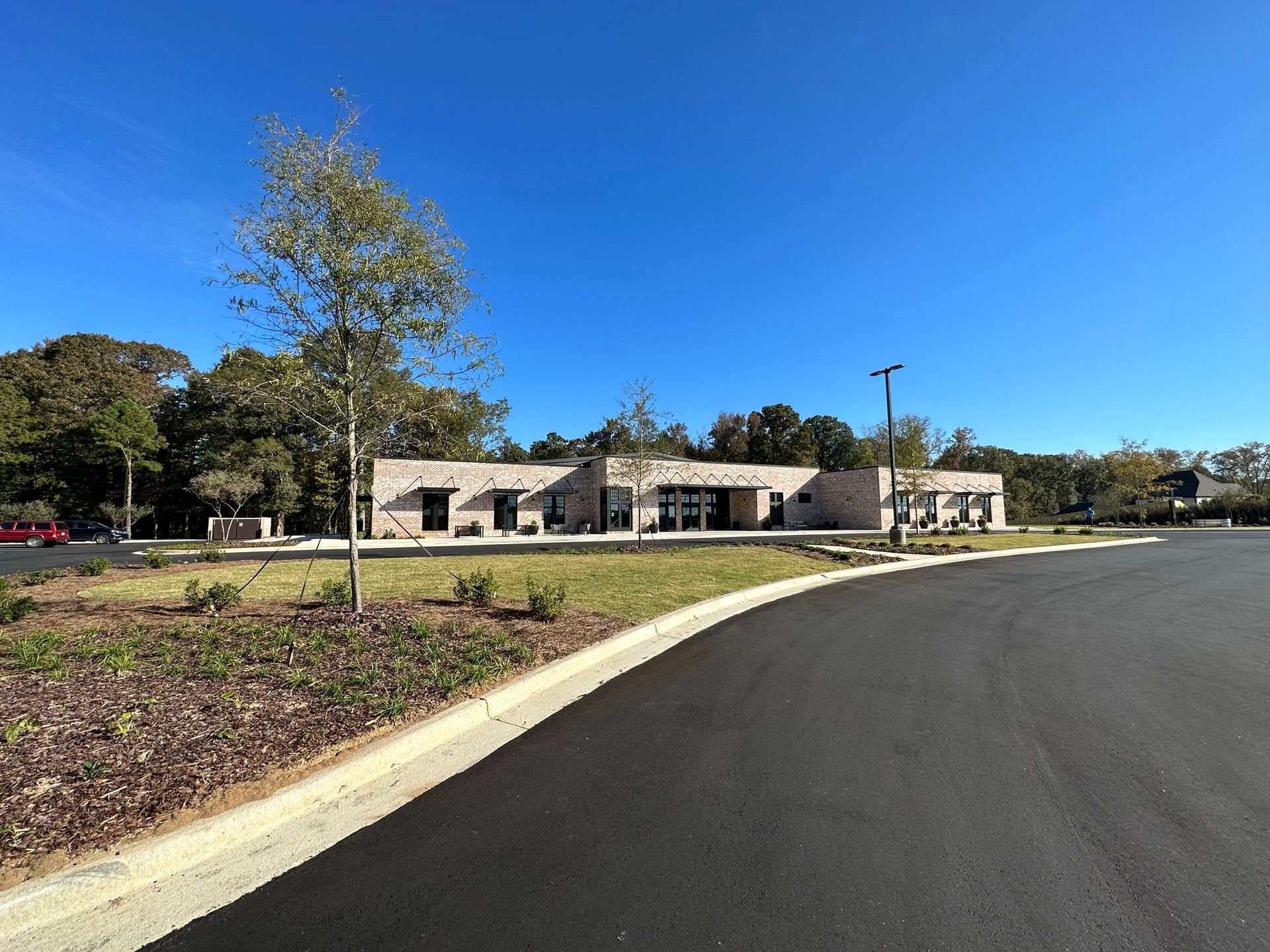 A large building is sitting on the side of a road next to a parking lot.