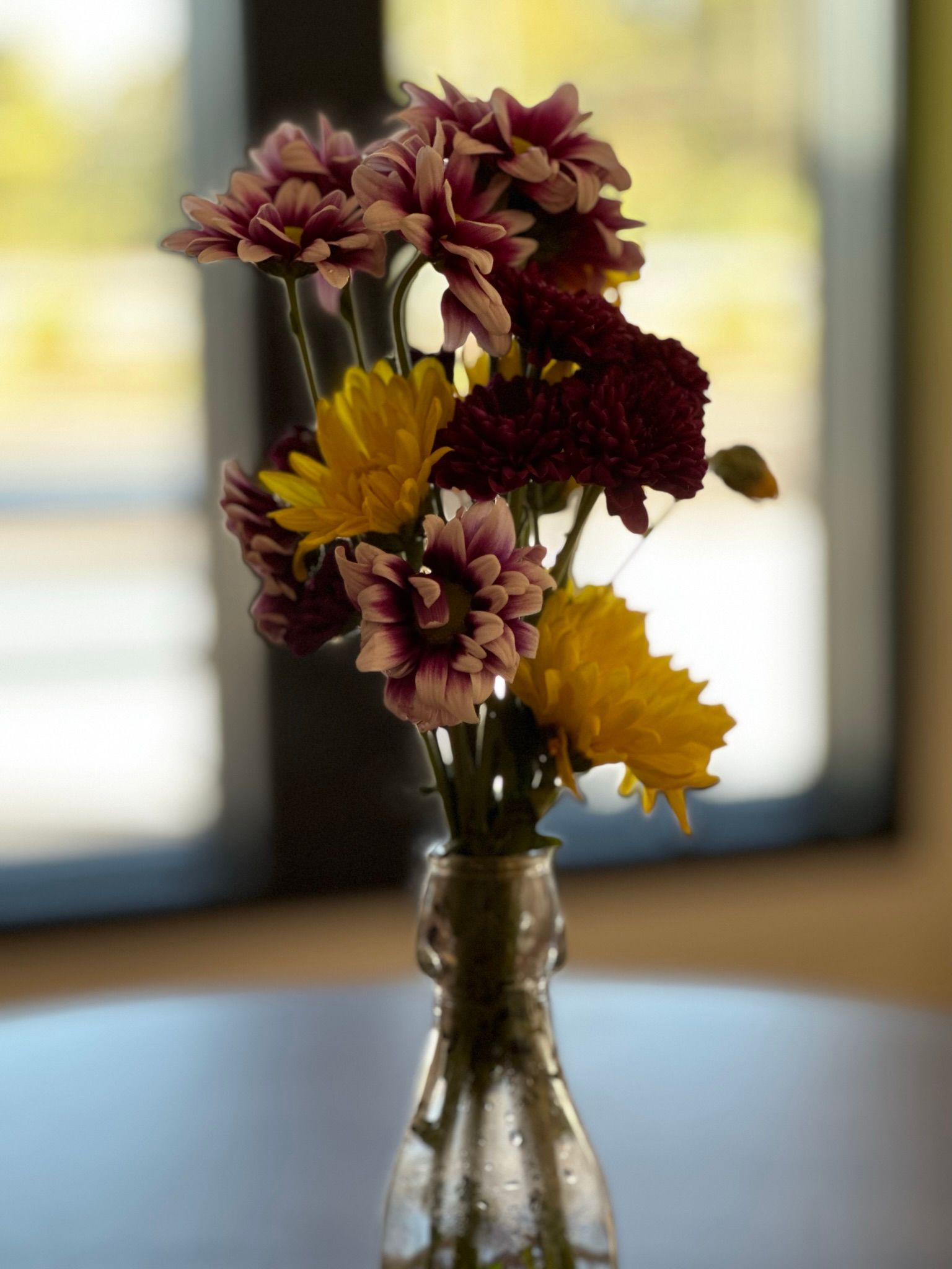 Purple and yellow flowers in a clear vase on a table