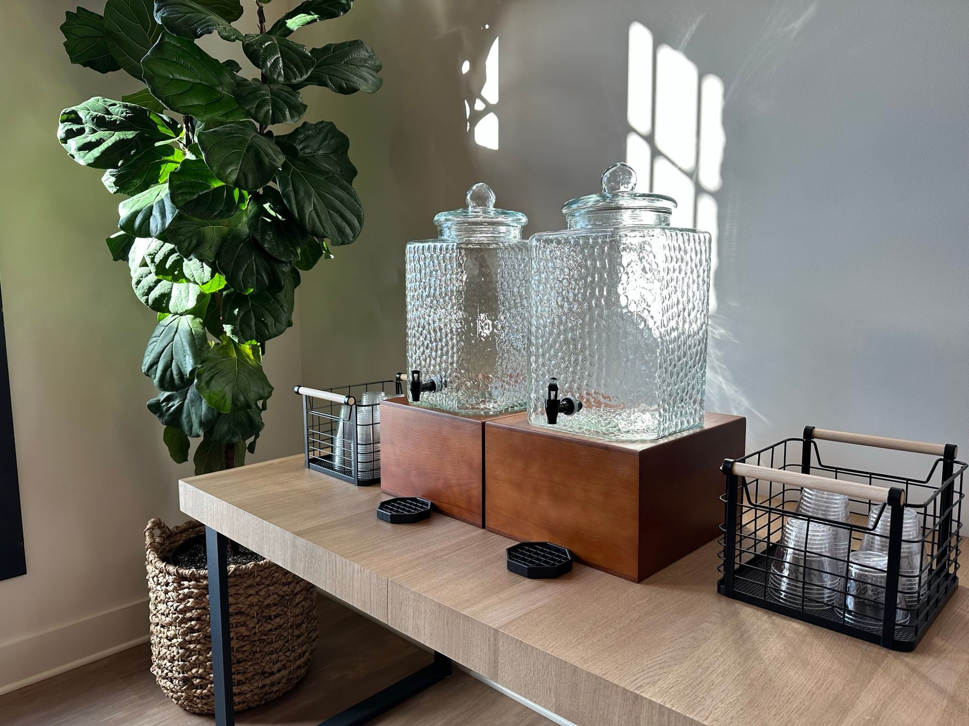 A wooden table with three glass jars on it and a plant in the background.