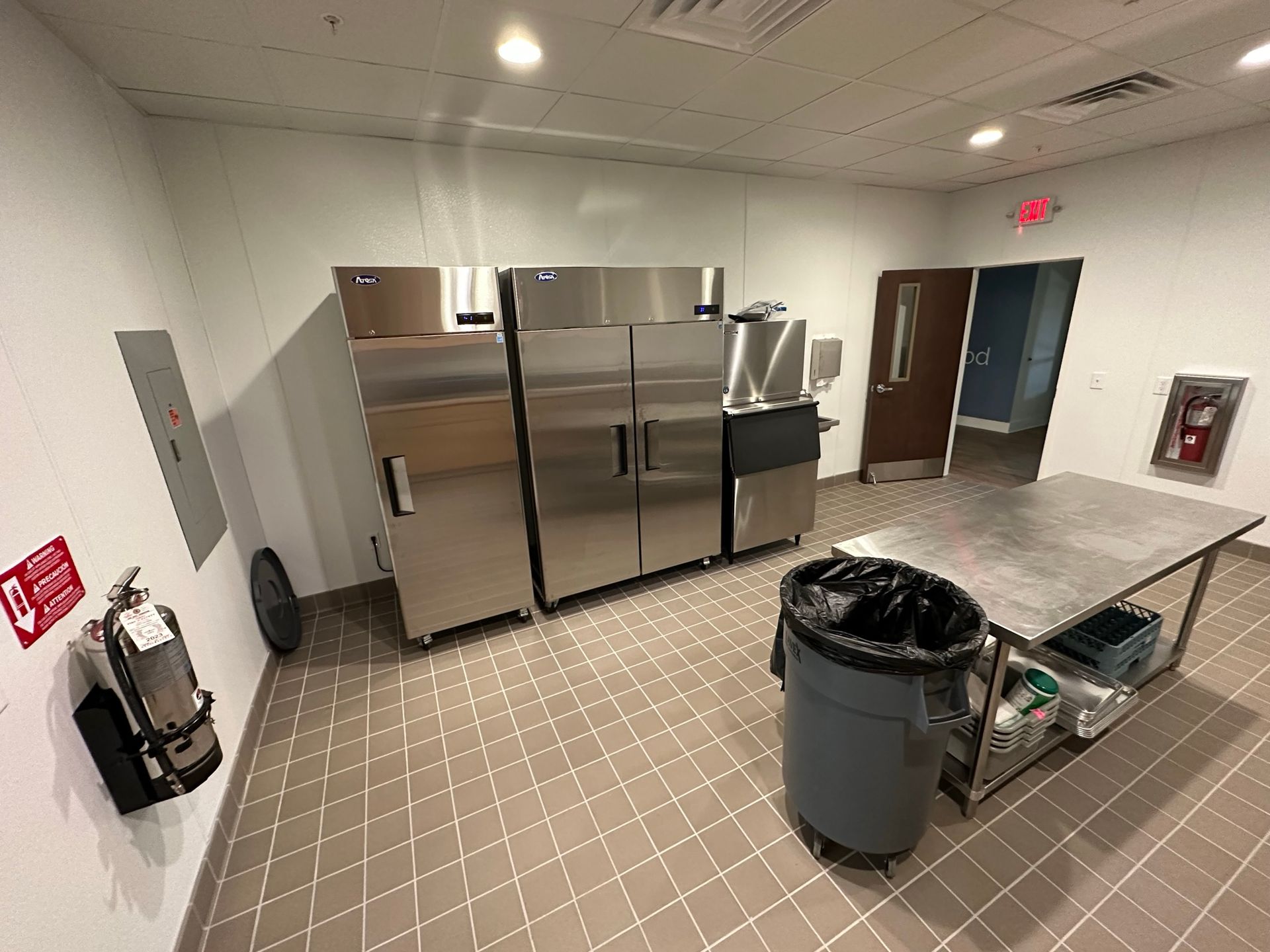 A kitchen with stainless steel refrigerators and a table.