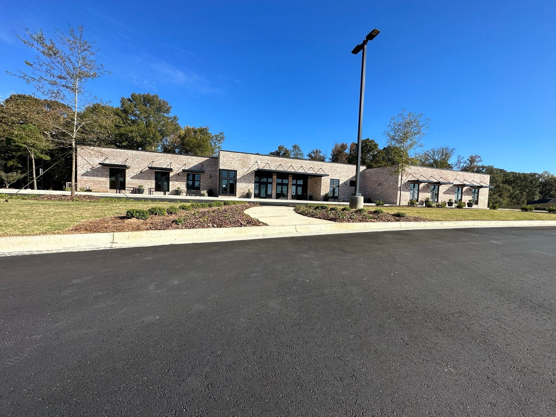 A large building with a lot of windows is sitting on the side of a road.
