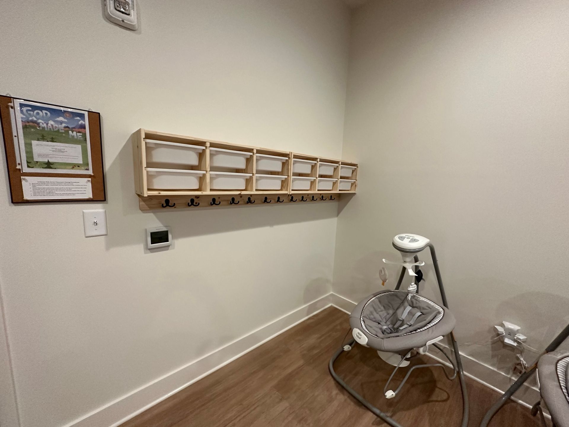 A room with a crib and a swing in it.