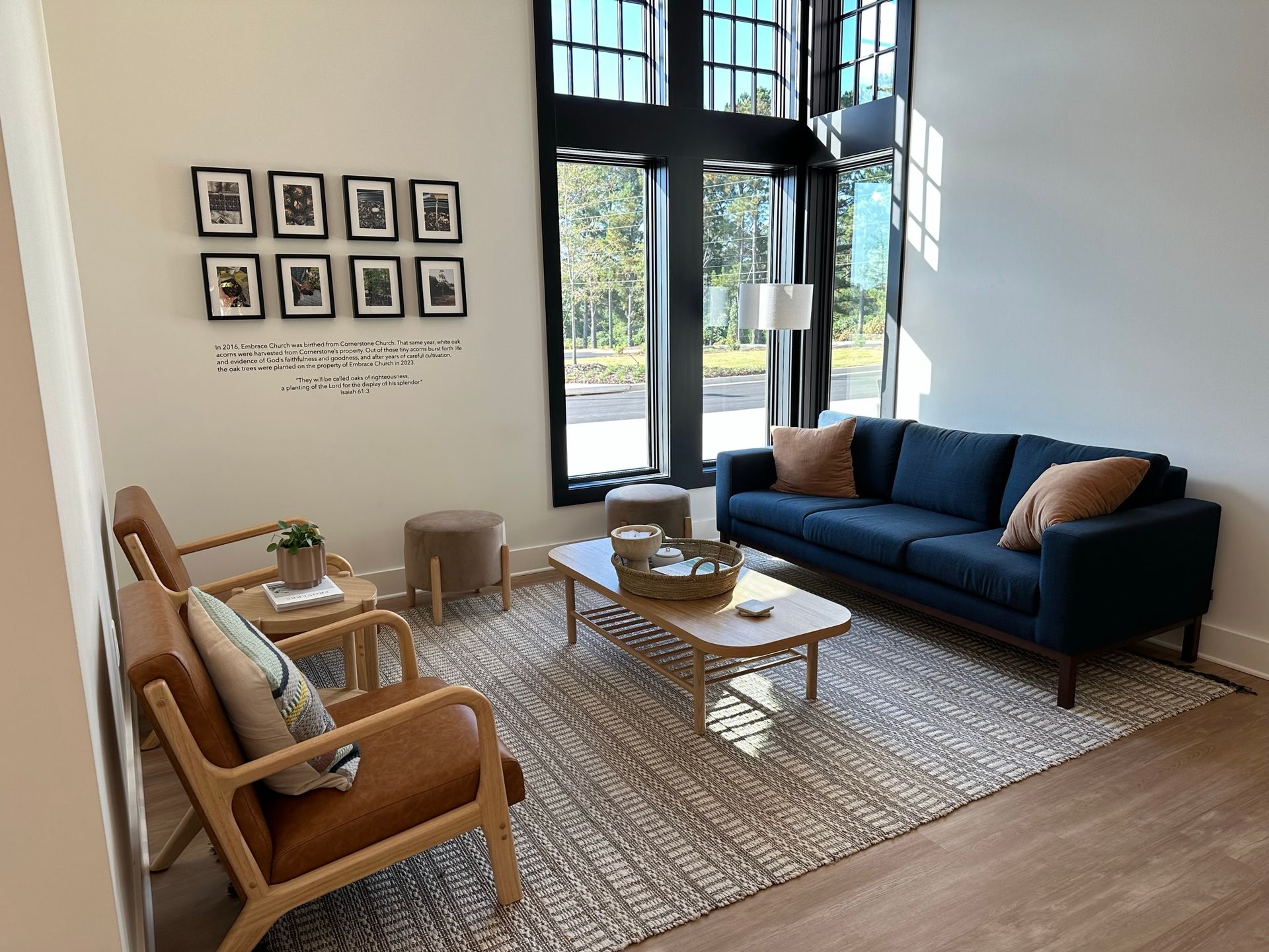 A living room with a blue couch , two chairs , a coffee table and a rug.