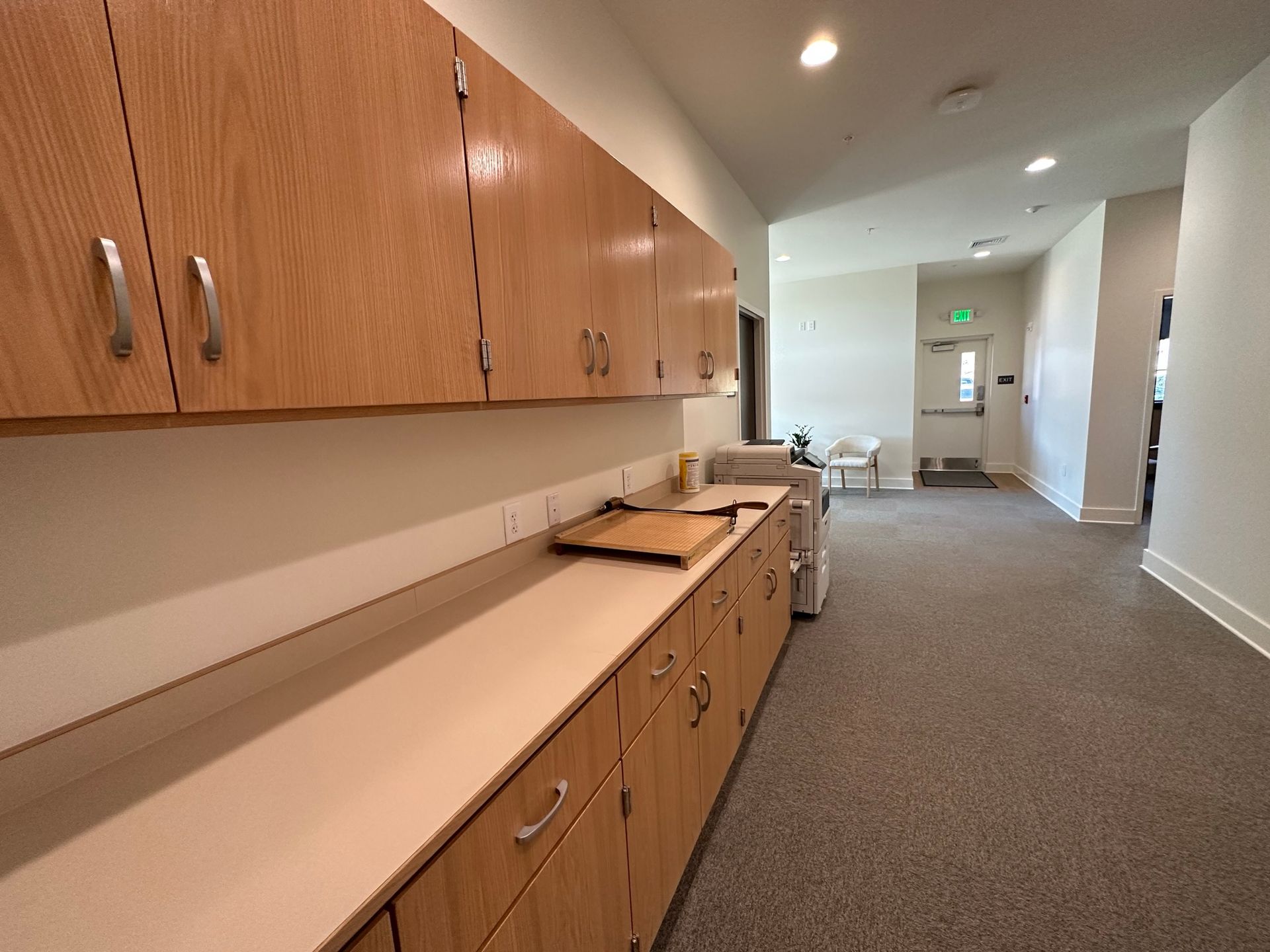 A long hallway with wooden cabinets and white counter tops
