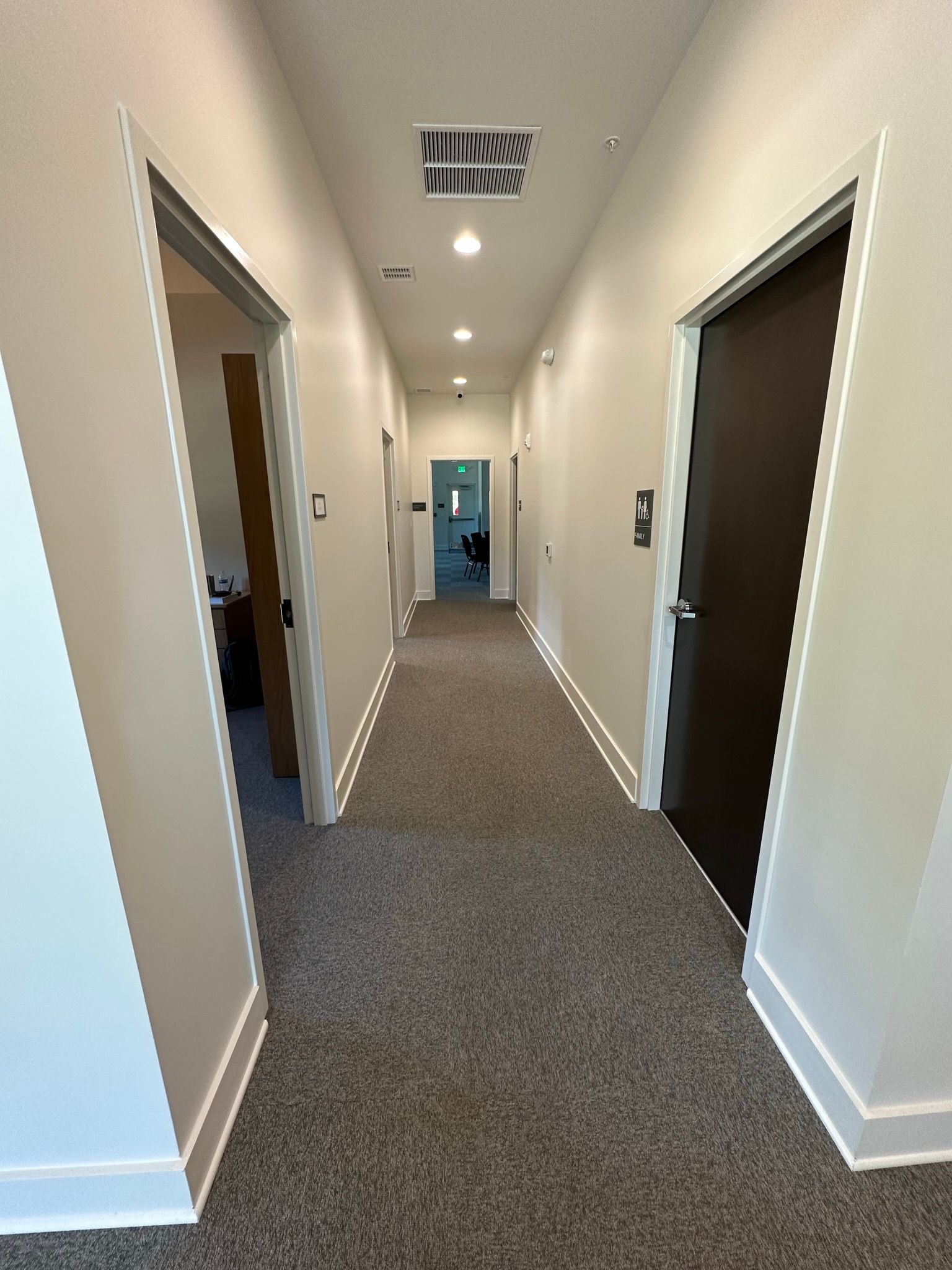 A long hallway with a carpeted floor and two doors leading to different rooms.