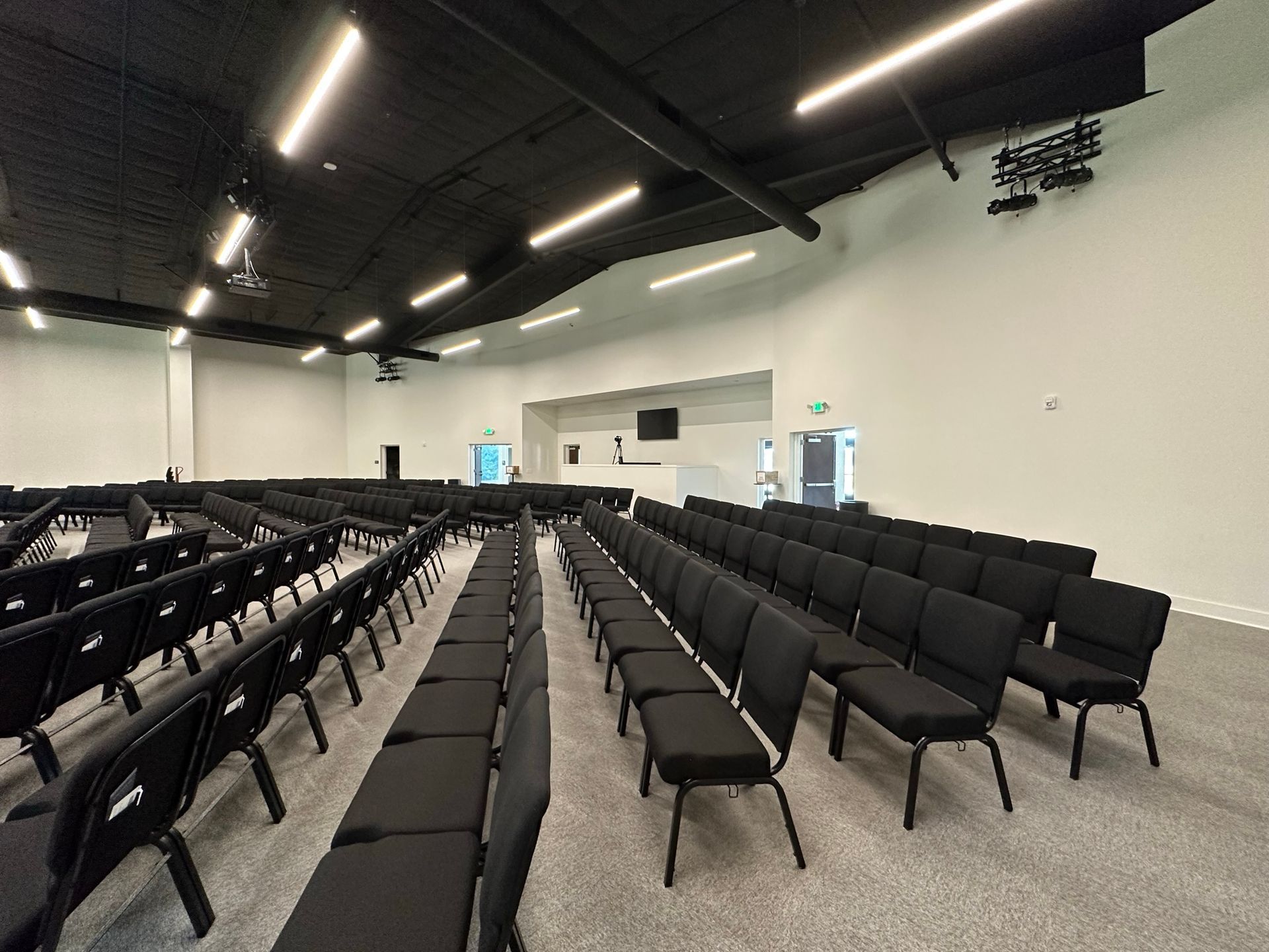 Rows of black chairs are lined up in a large auditorium.