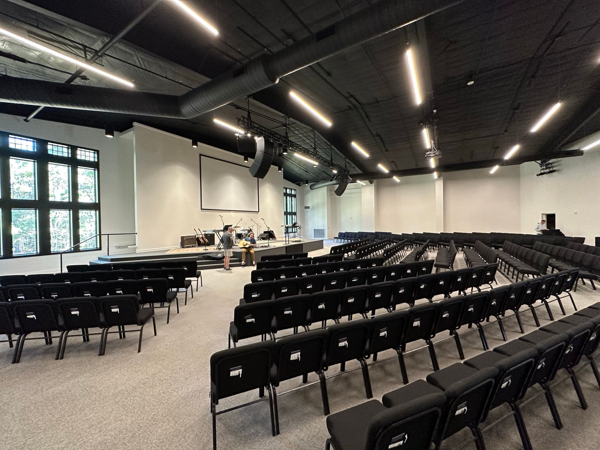 A large auditorium with rows of chairs and a large screen