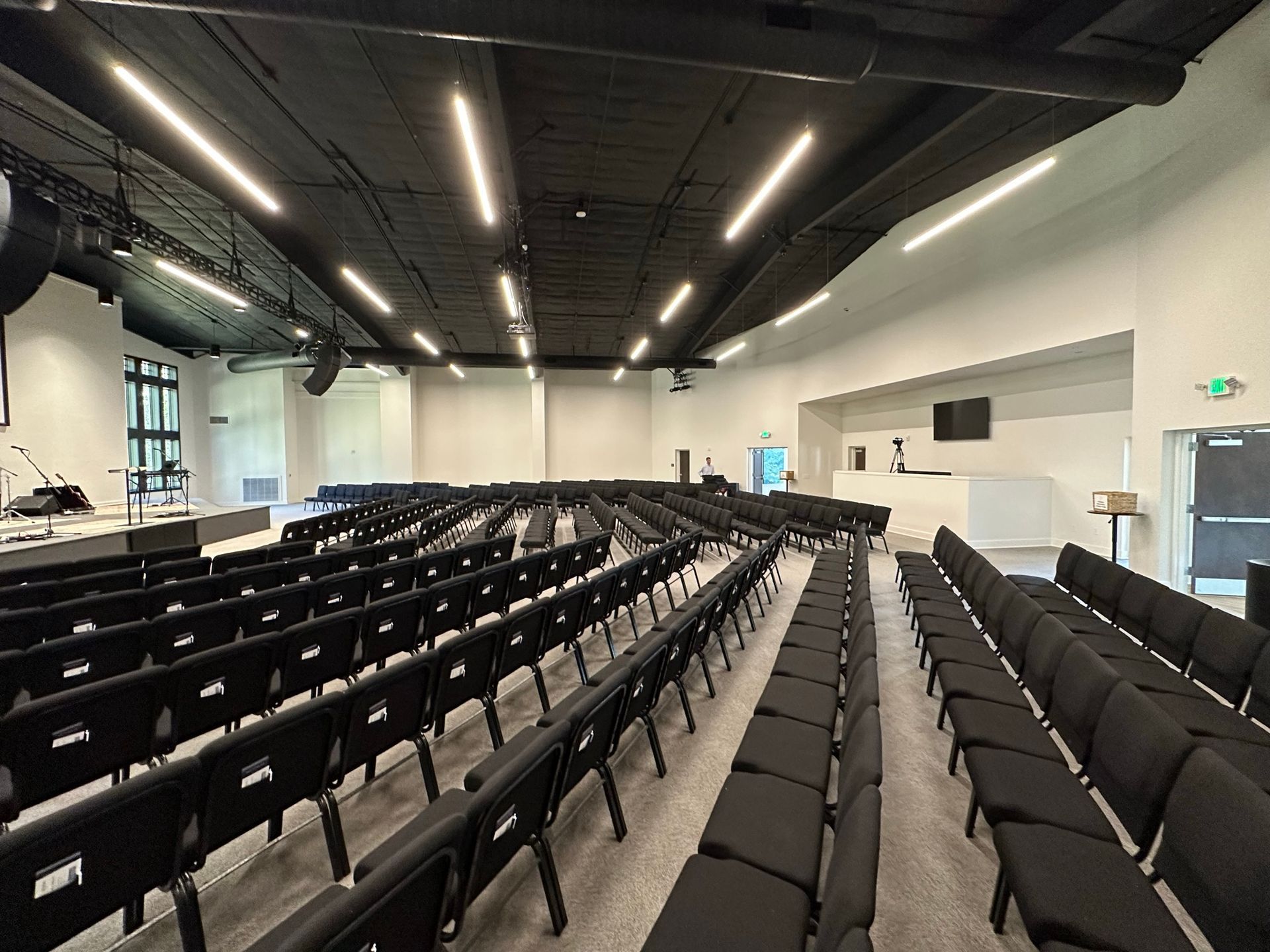 A large auditorium filled with rows of black chairs.