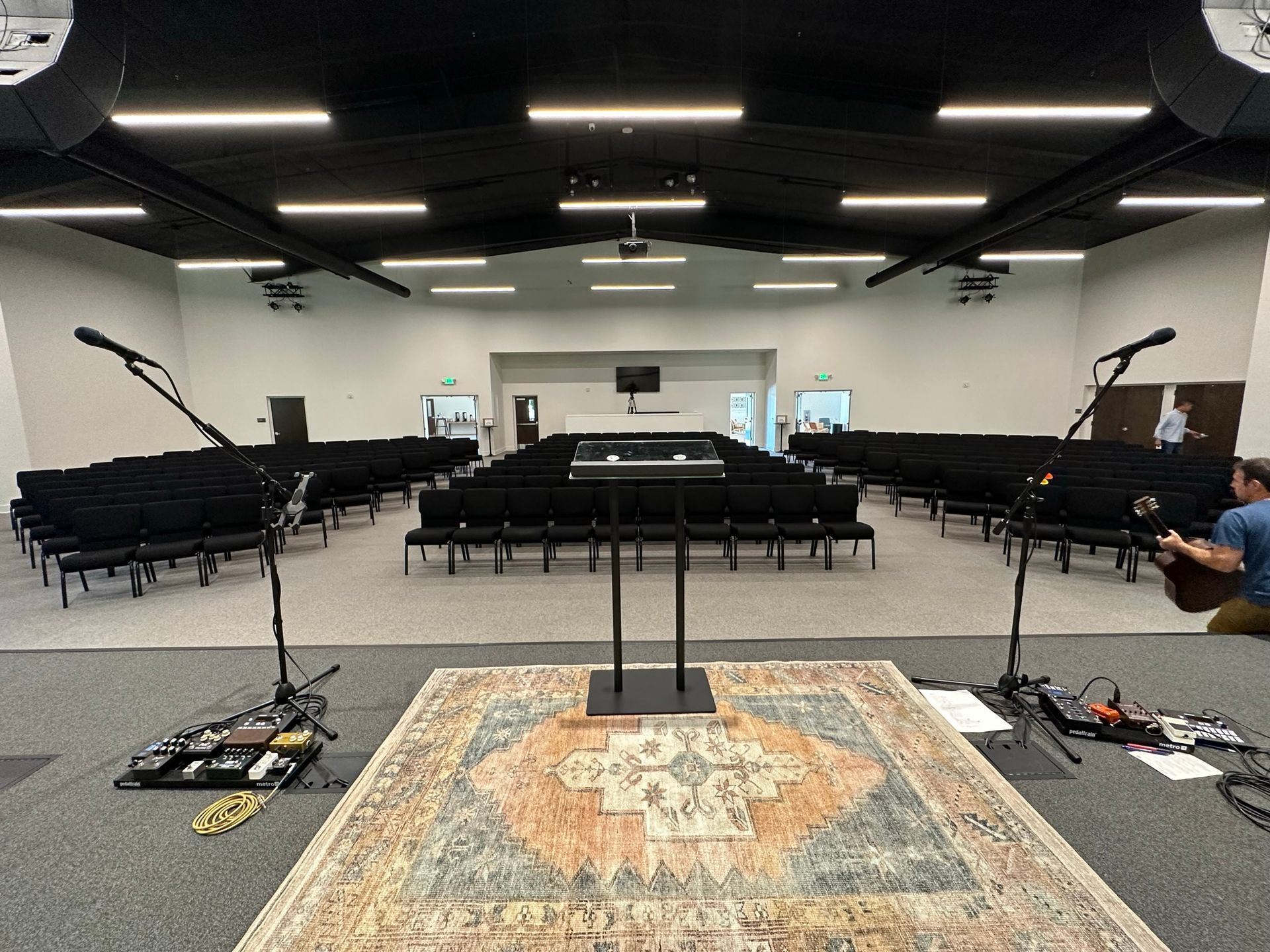 A man is playing a guitar in front of a large auditorium.