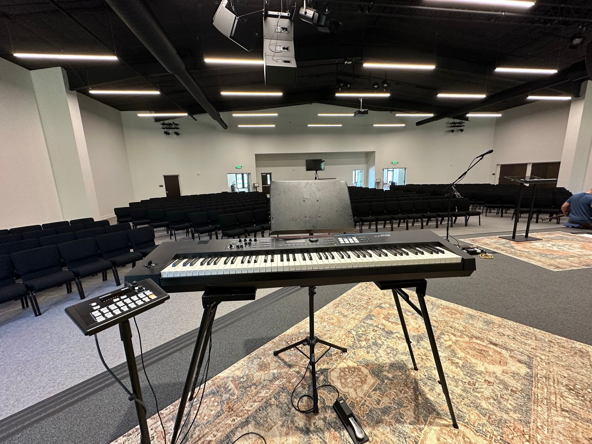 A keyboard is sitting on a stand in a large room.