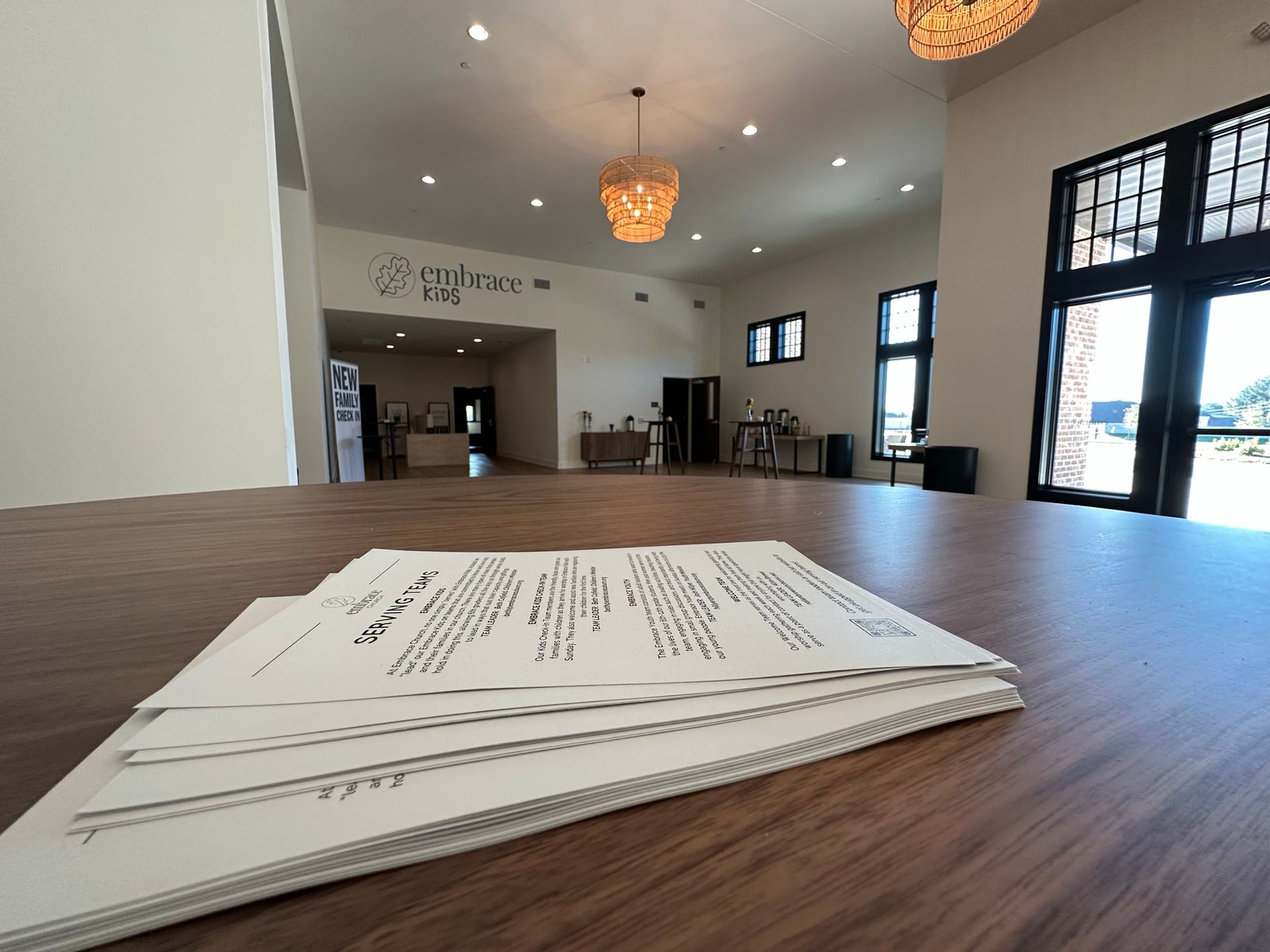 A stack of papers is sitting on a wooden table in a room.