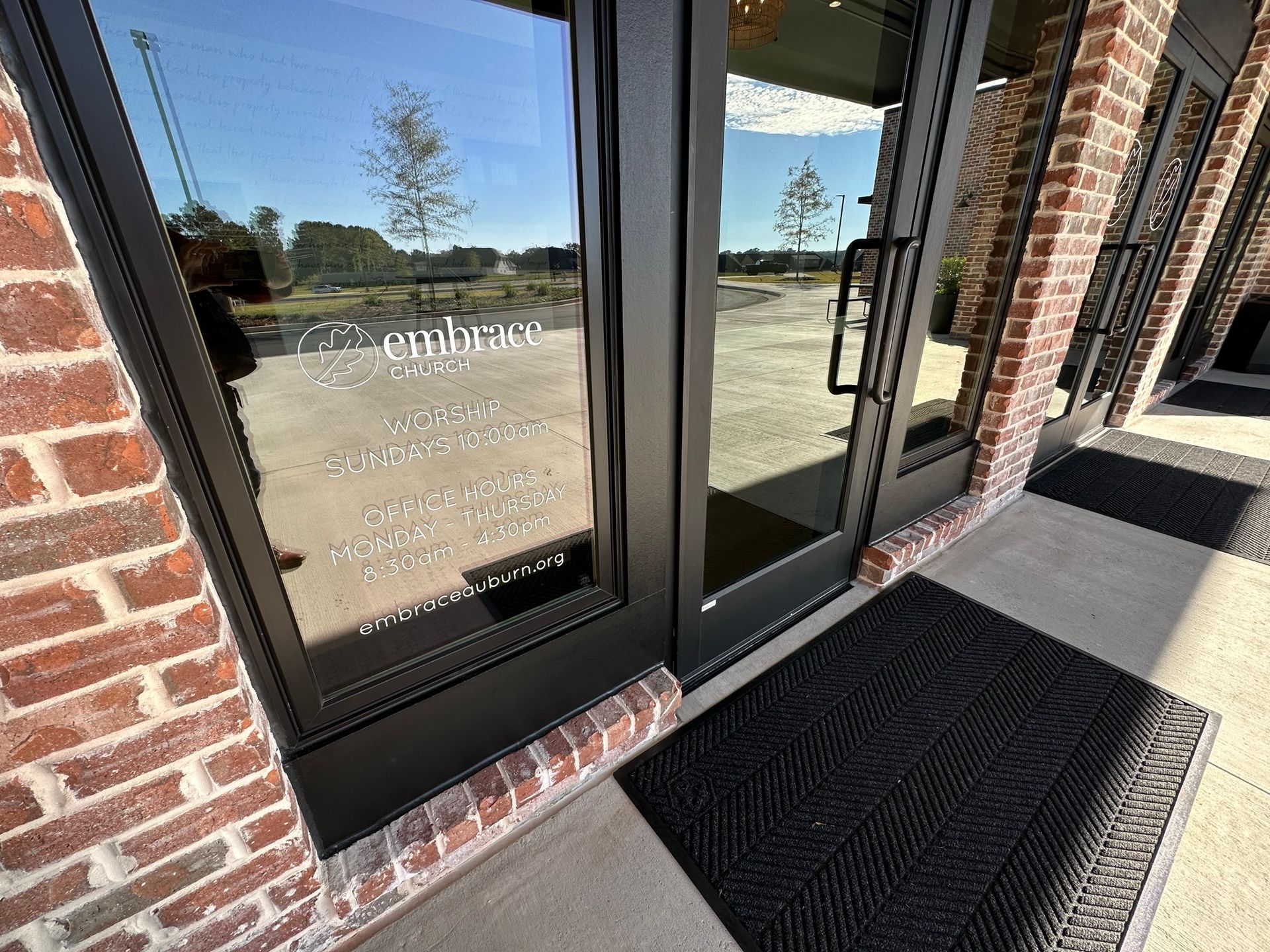 A brick building with a black door and a black mat in front of it.