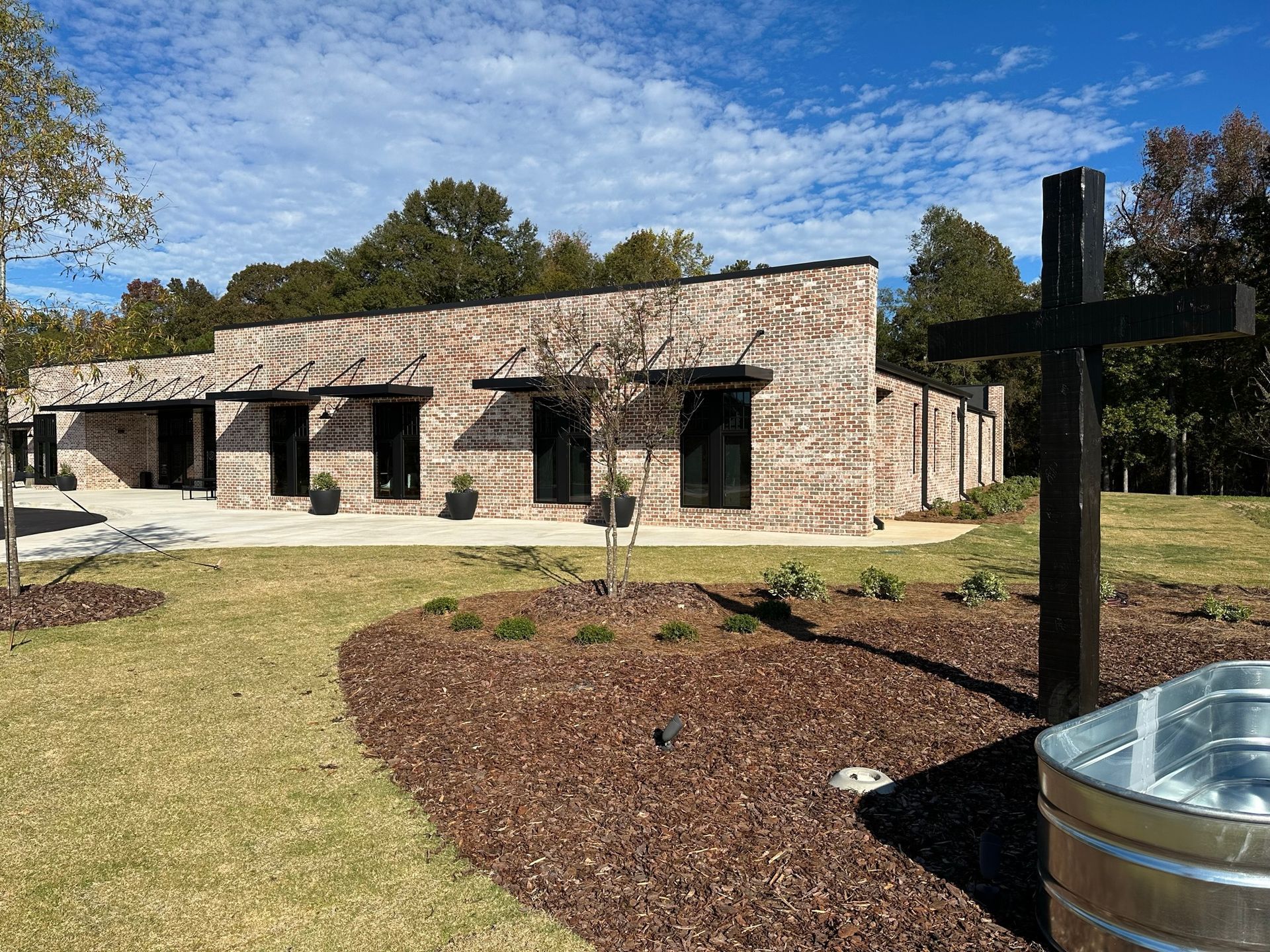 A large brick building with a cross in front of it.
