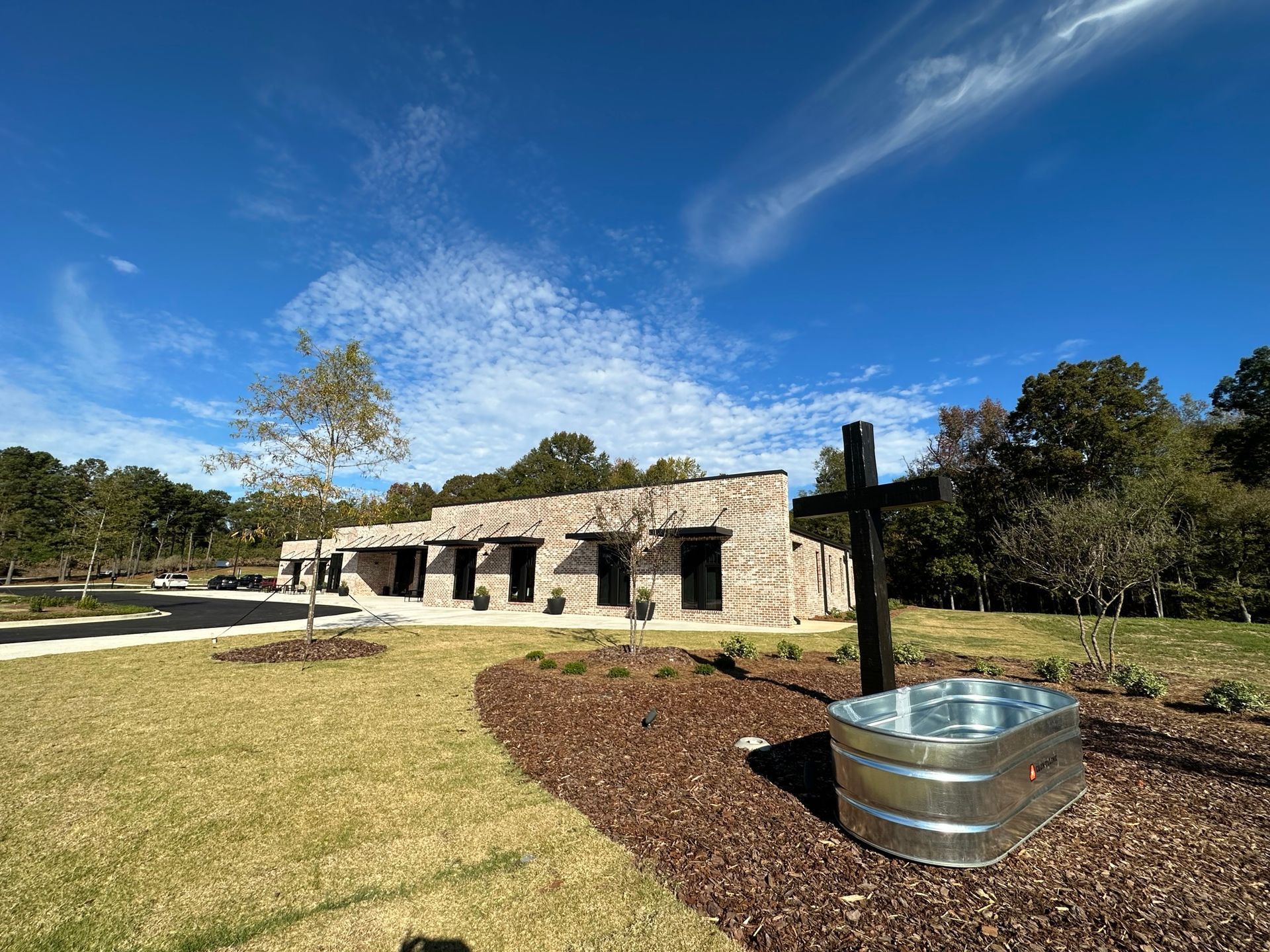 A metal tub with a cross in front of a building.