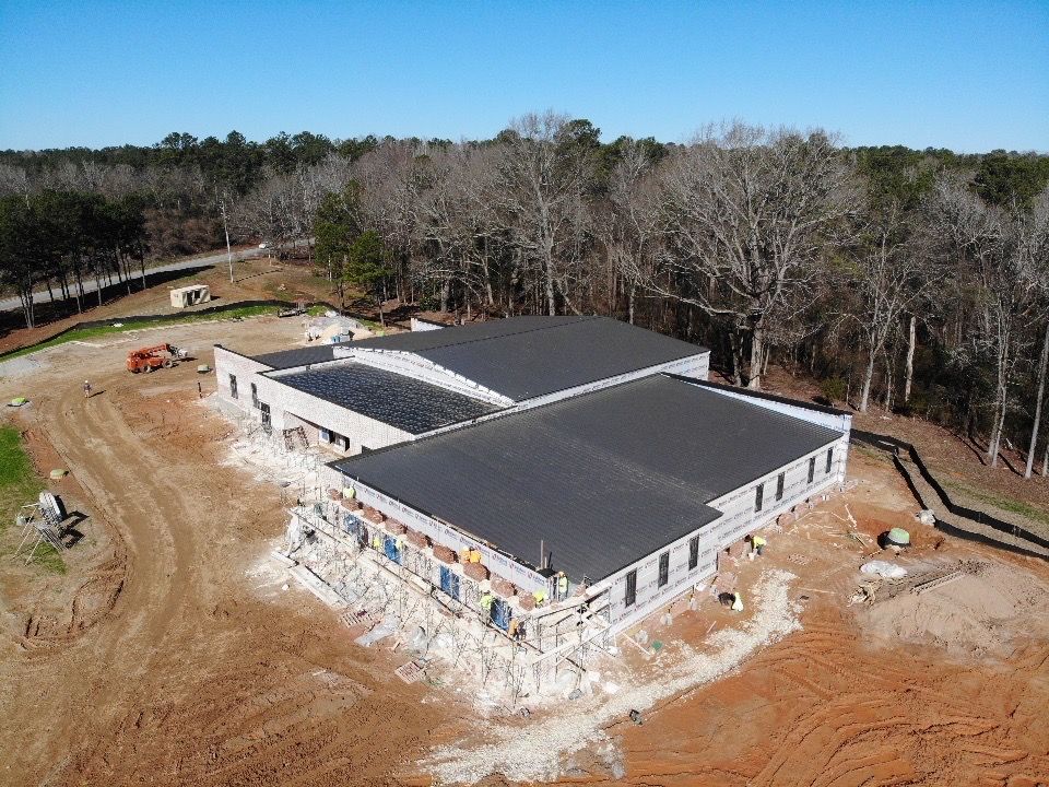 An aerial view of a building under construction in the middle of a forest.