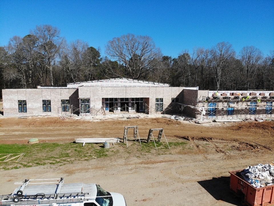 A white truck is parked in front of a building under construction