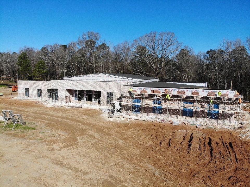 A large building is being built in the middle of a dirt field.