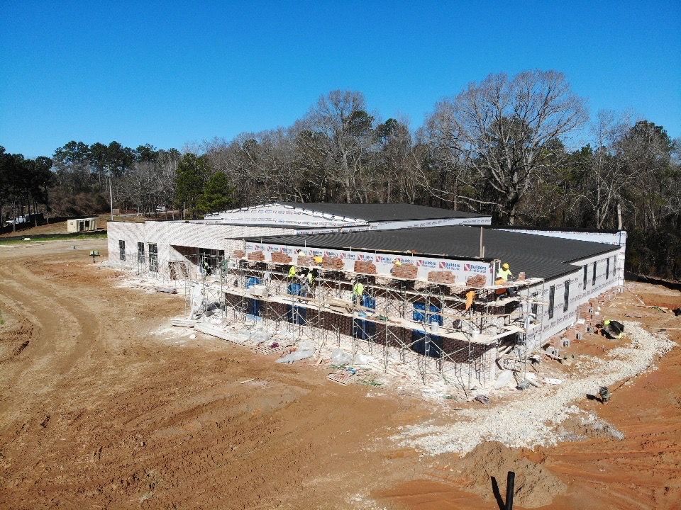 An aerial view of a building under construction in the middle of a dirt field.
