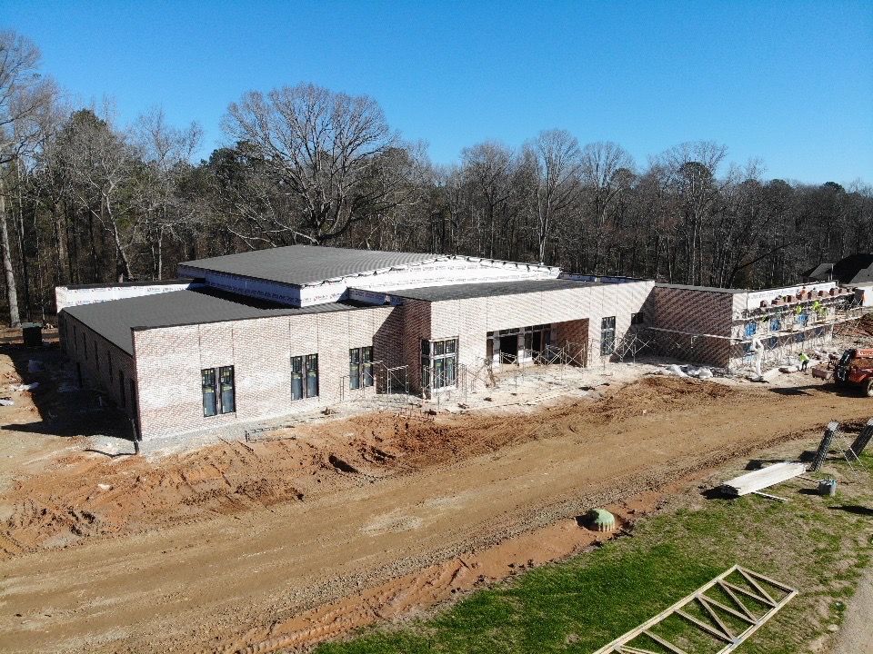 An aerial view of a building under construction in the middle of a dirt road.