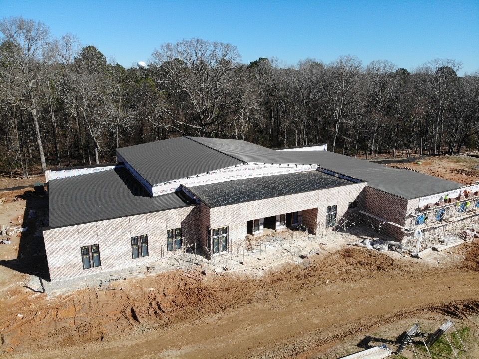 An aerial view of a building under construction in the middle of a forest.