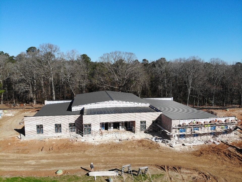 An aerial view of a large building under construction in the middle of a forest.