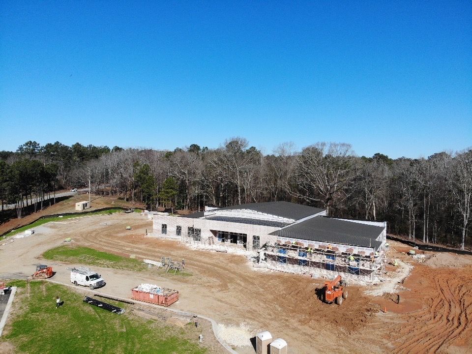 An aerial view of a building under construction in the middle of a forest.