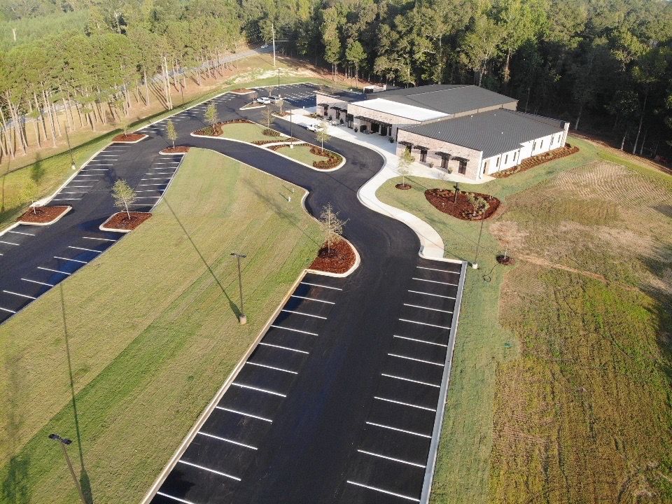 An aerial view of a parking lot with a building in the background