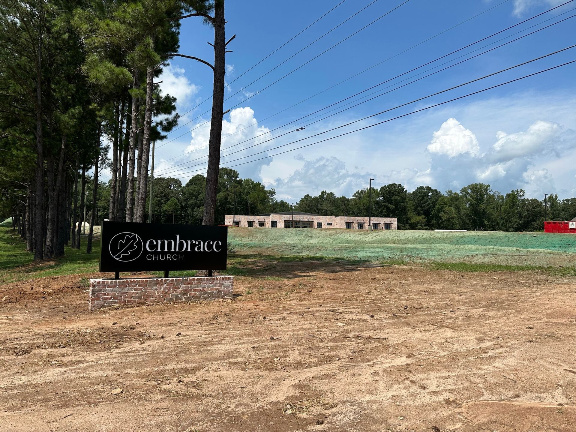 A sign that says embrace is in the middle of a dirt field.
