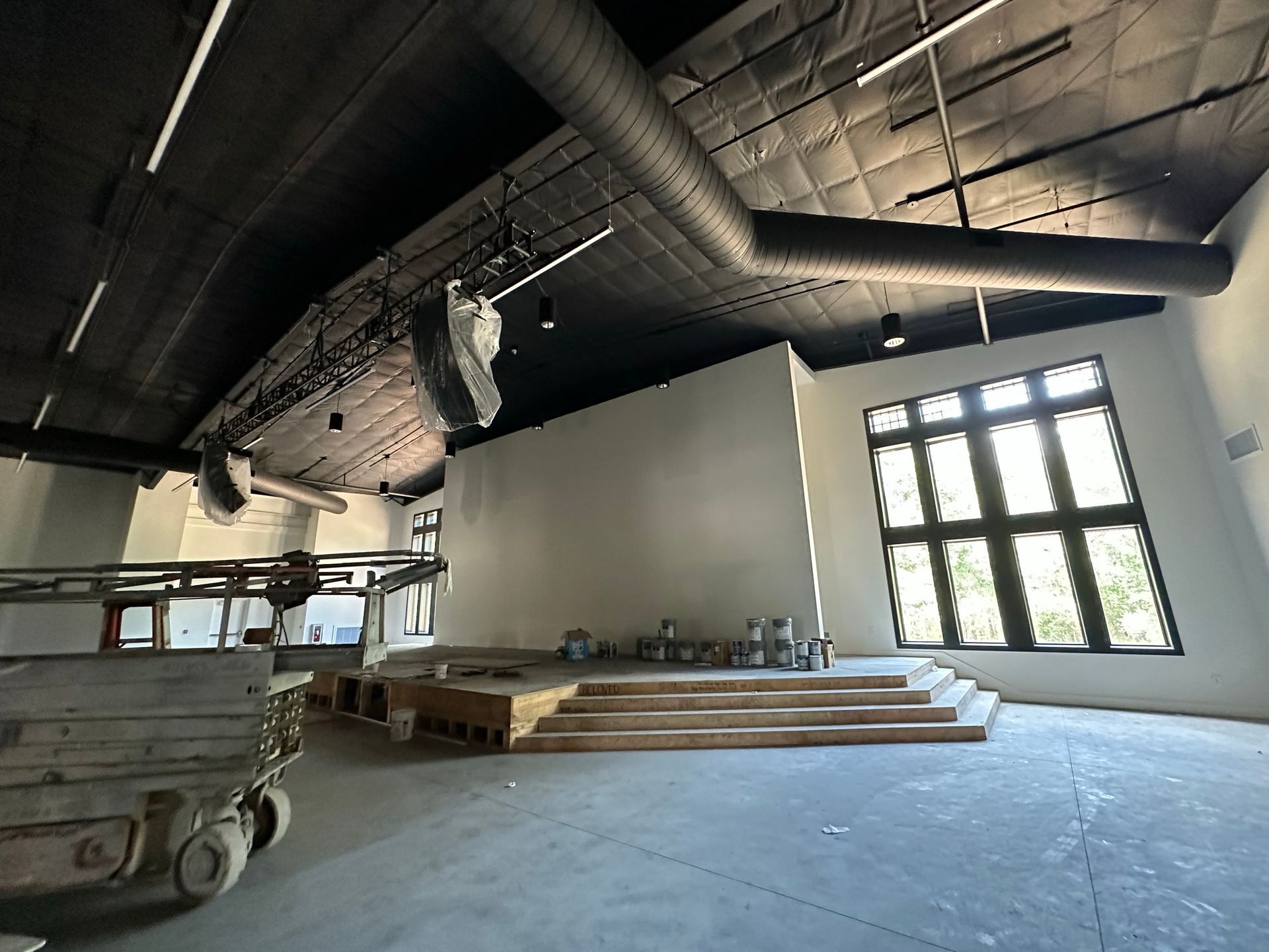 A large room with a lot of windows and pipes hanging from the ceiling.