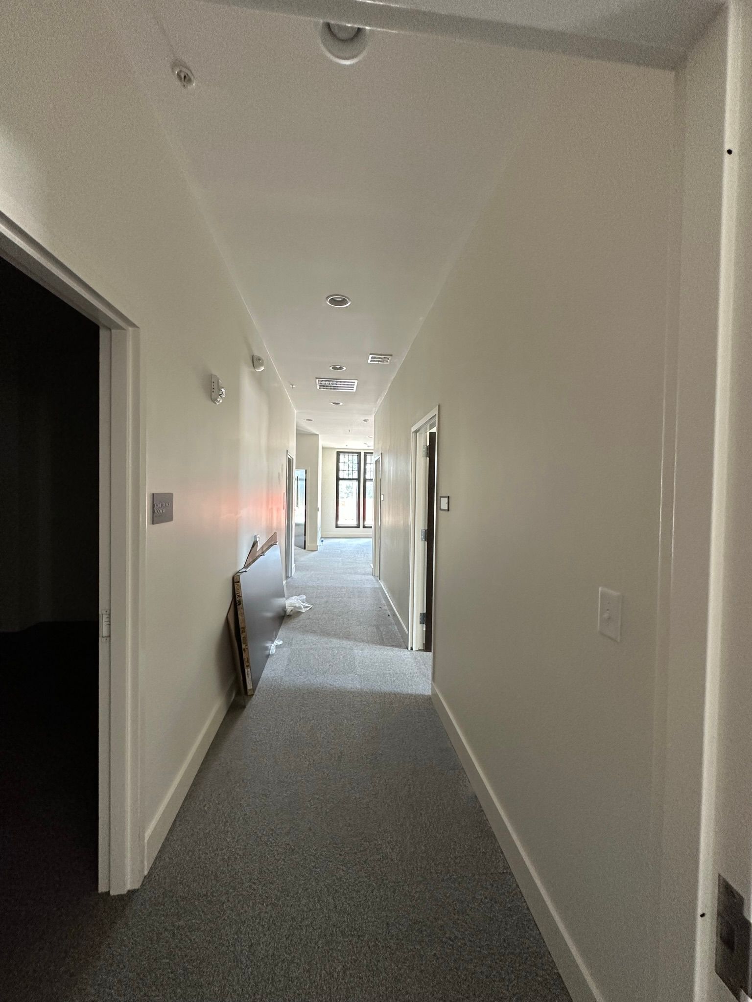 A long hallway with a carpeted floor and white walls.
