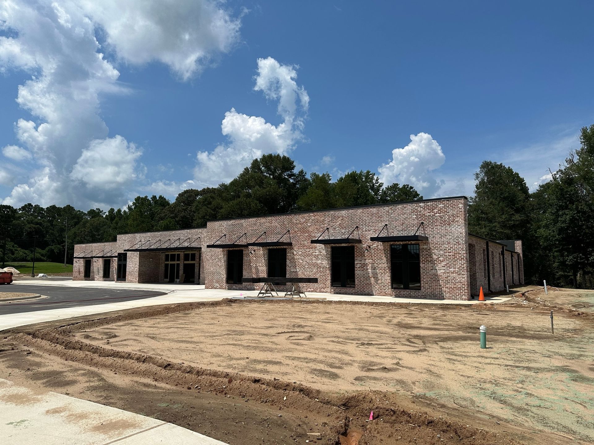 A large brick building is being built in the middle of a dirt field.