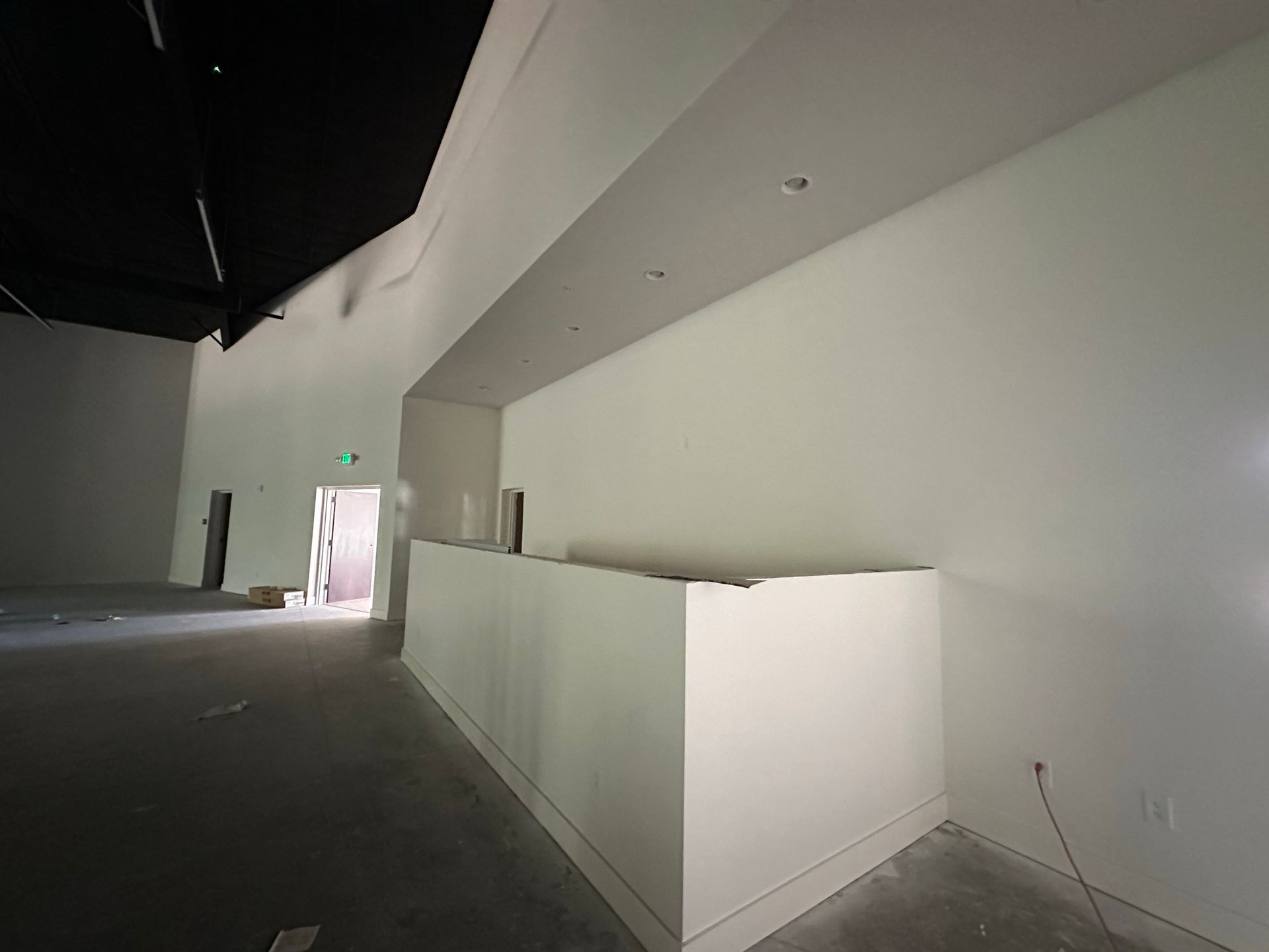A large empty room with white walls and a black ceiling.