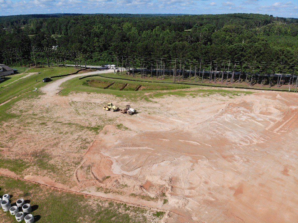 An aerial view of a dirt field with trees in the background.