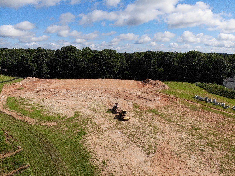 An aerial view of a large dirt field with trees in the background.